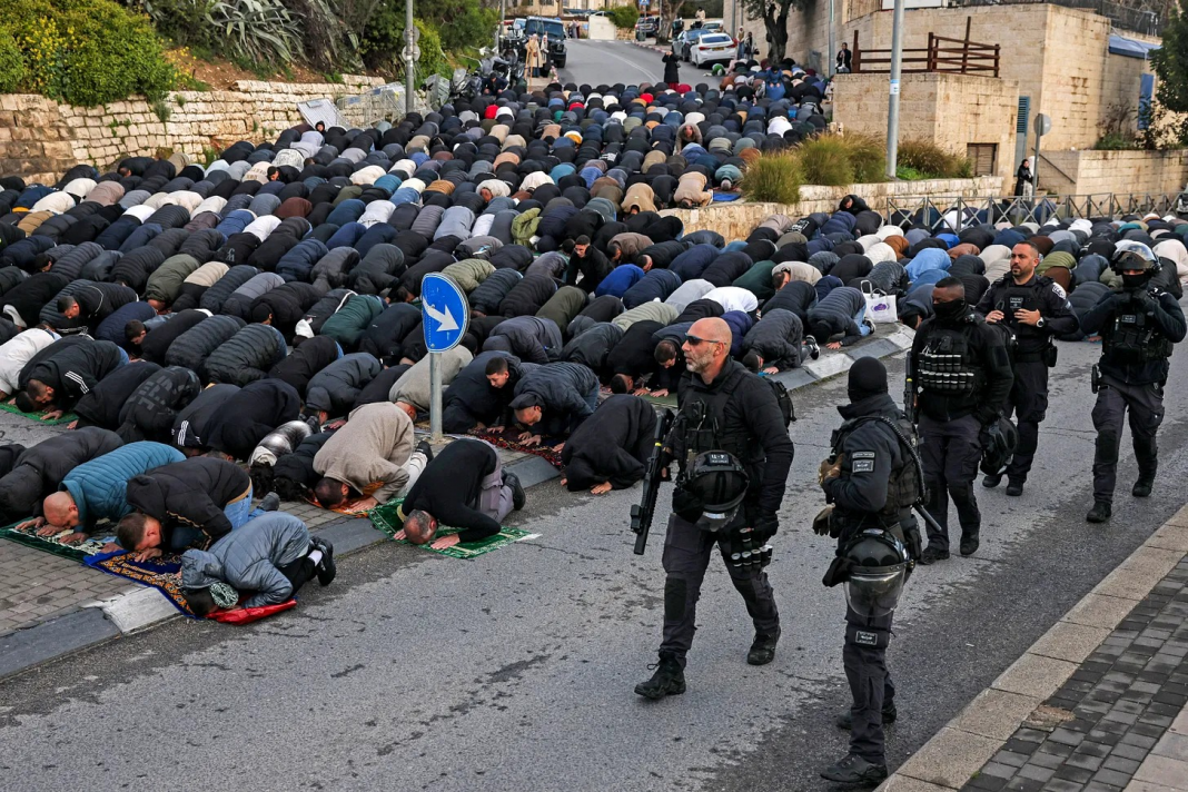 e 20 mars 2026, des soldats israéliens passent devant des fidèles musulmans rassemblés pour la prière matinale de l'Aïd al-Fitr, à l'extérieur des remparts de la vieille ville de Jérusalem. Photo : AHMAD GHARABLI / AFP via Getty Images.