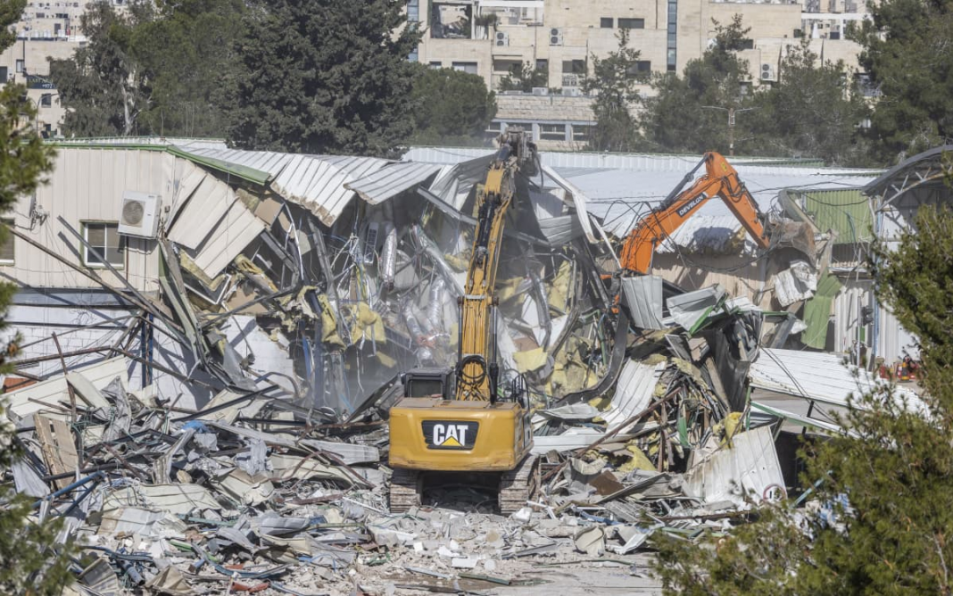 Une photographie montre des engins de démolition en train de détruire un bâtiment au sein du siège de l'Office de secours et de travaux des Nations unies (UNRWA), dans le quartier de Cheikh Jarrah, à Jérusalem-Est, annexée par Israël, le 20 janvier 2026. Crédit photo : ILIA YEFIMOVICH
